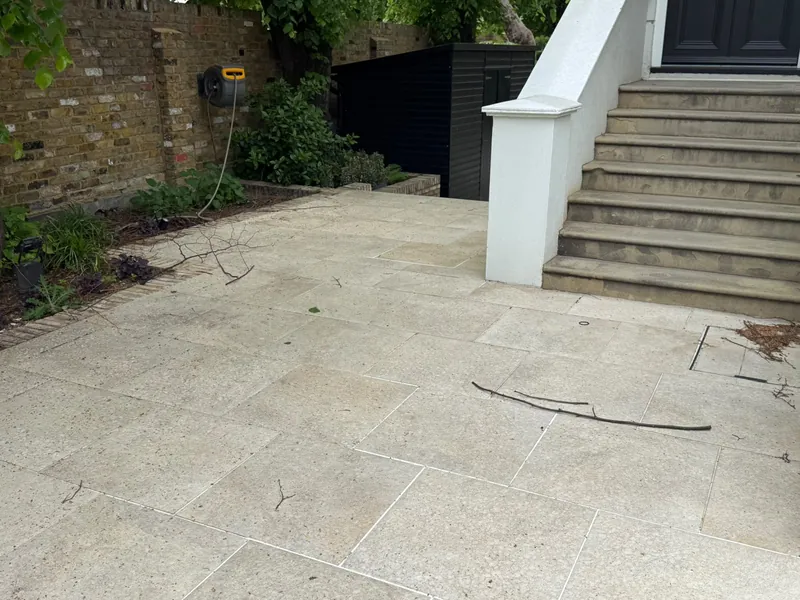 A pale stone patio below steps up to the house